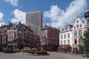 Vibrant Brussels city street with historic buildings, cafes, and modern skyscraper under a clear blue sky.